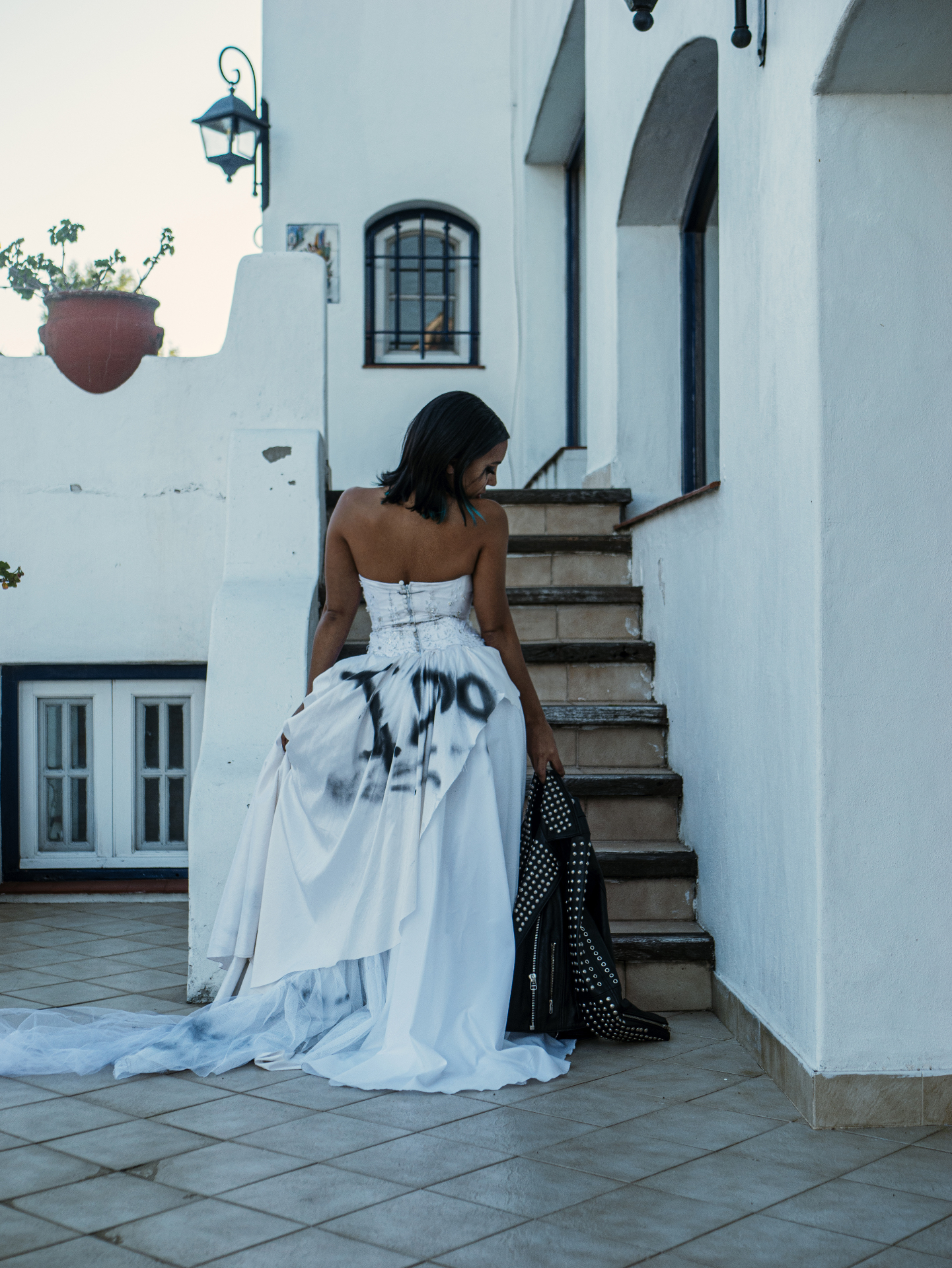 Genrey in a graffiti'd wedding gown holding a studded jacket