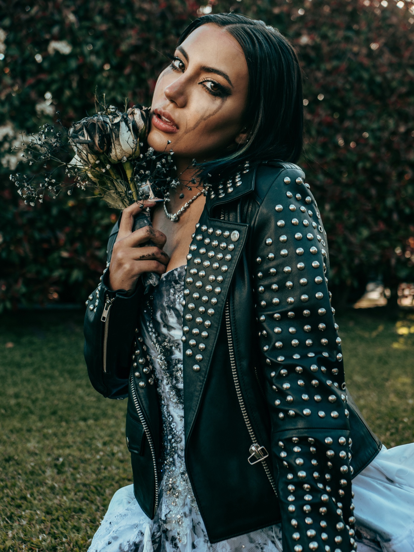 Genrey in a studded leather jacket holding dried roses